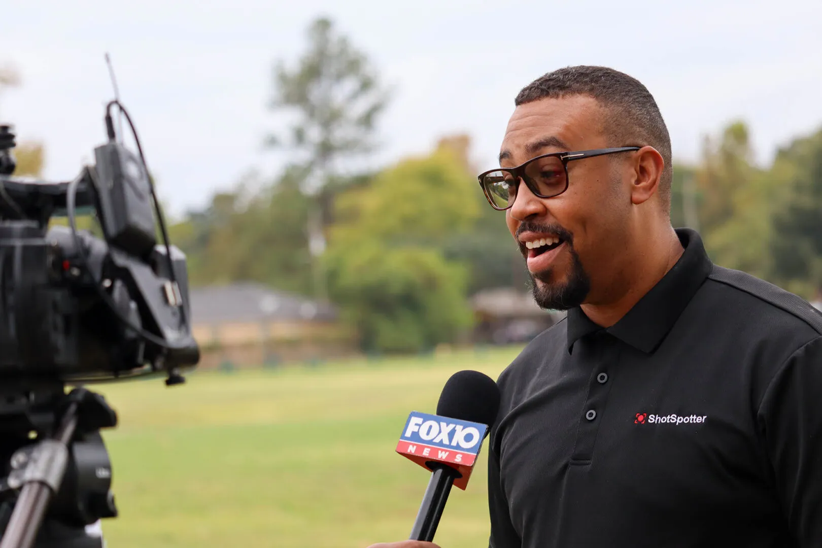 a man in a black shirt is talking to a reporter