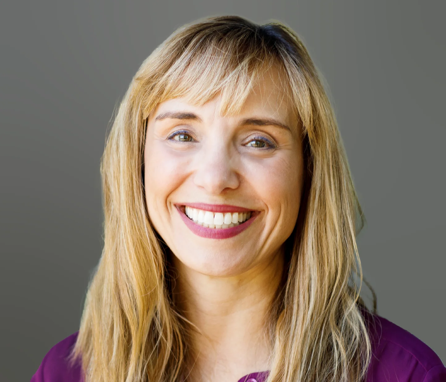 a woman with long blonde hair smiling at the camera