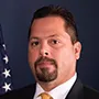 a man in a suit and tie in front of an american flag