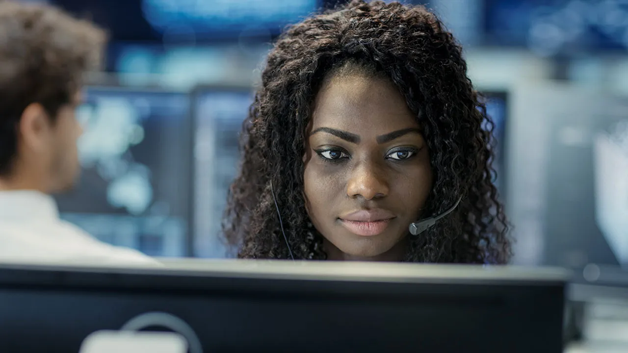 a woman with a headset looking at a computer screen