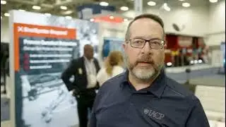 Video: a man with glasses standing in front of a poster