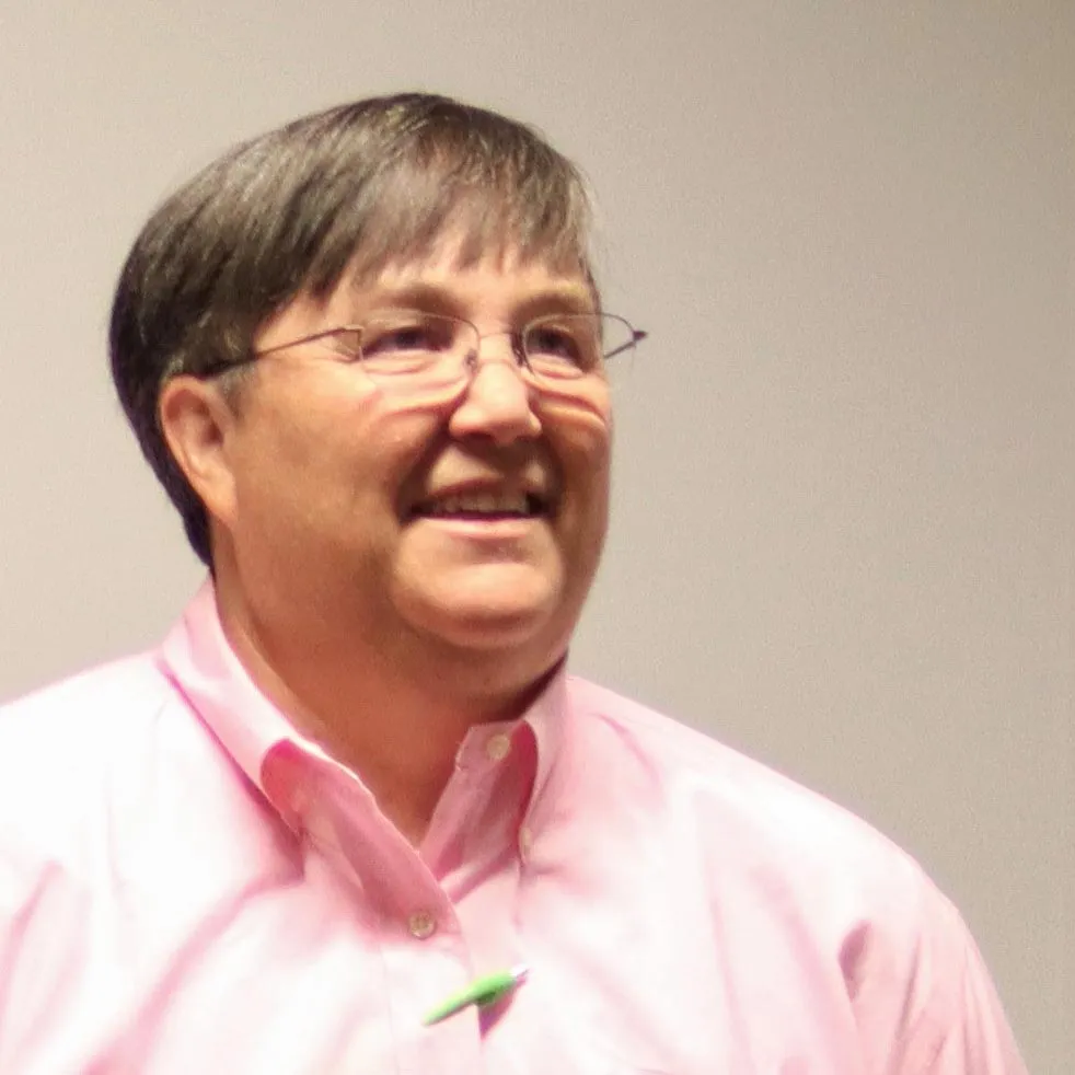 a man wearing glasses and a pink shirt