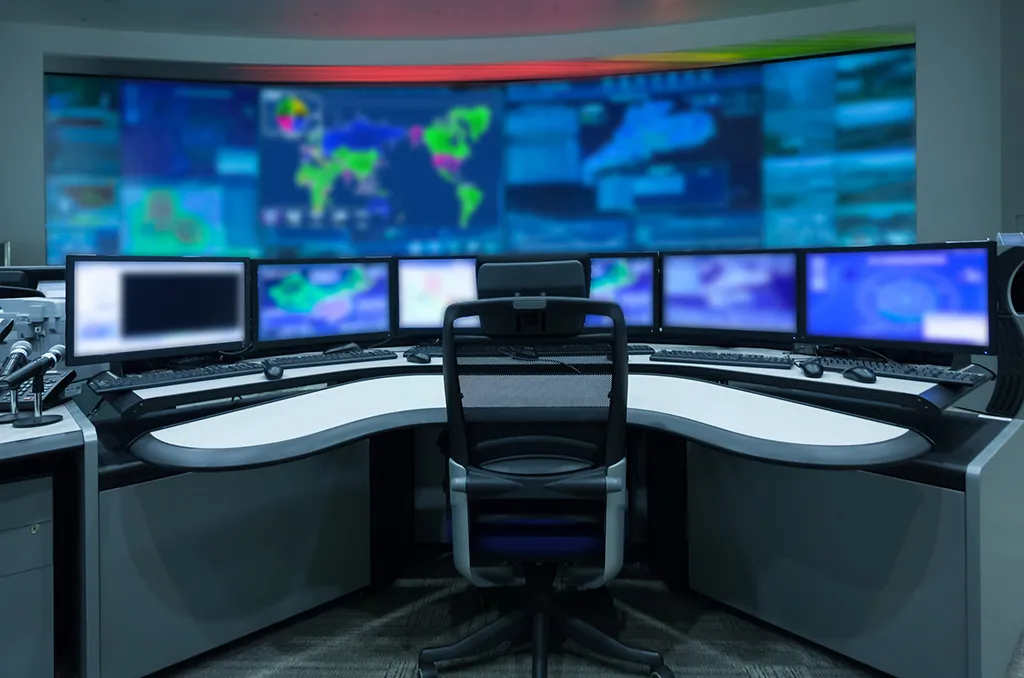 a desk with multiple monitors and a chair in front of it